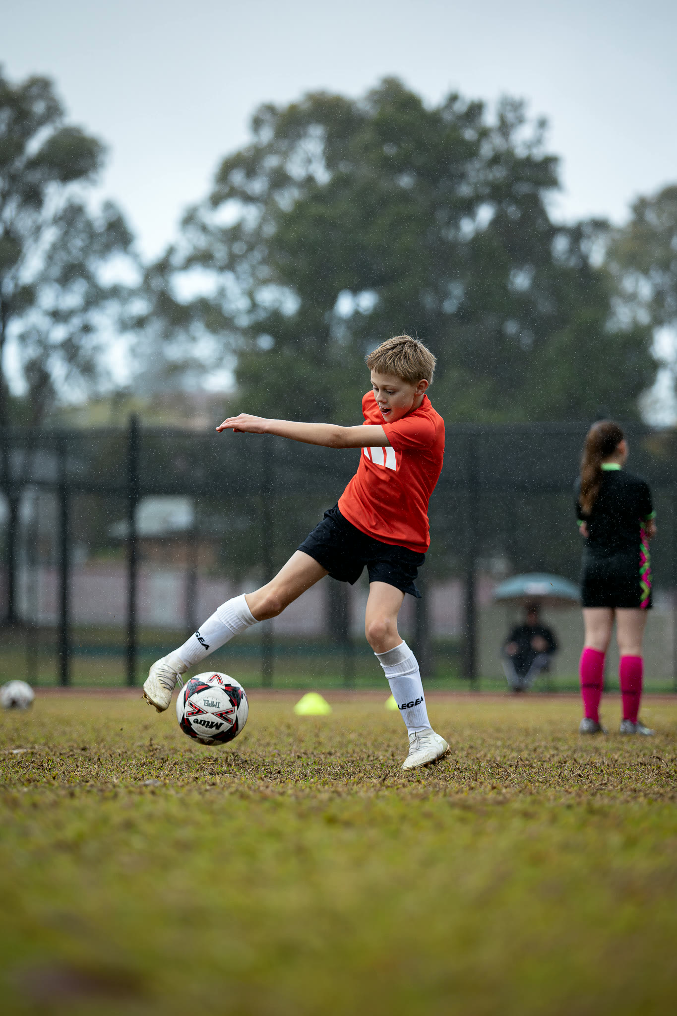 A young Gamechanger player striking the ball in the rain during a private session.