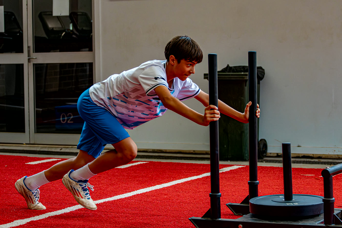 An athlete driving a weighted sled during a strength session.